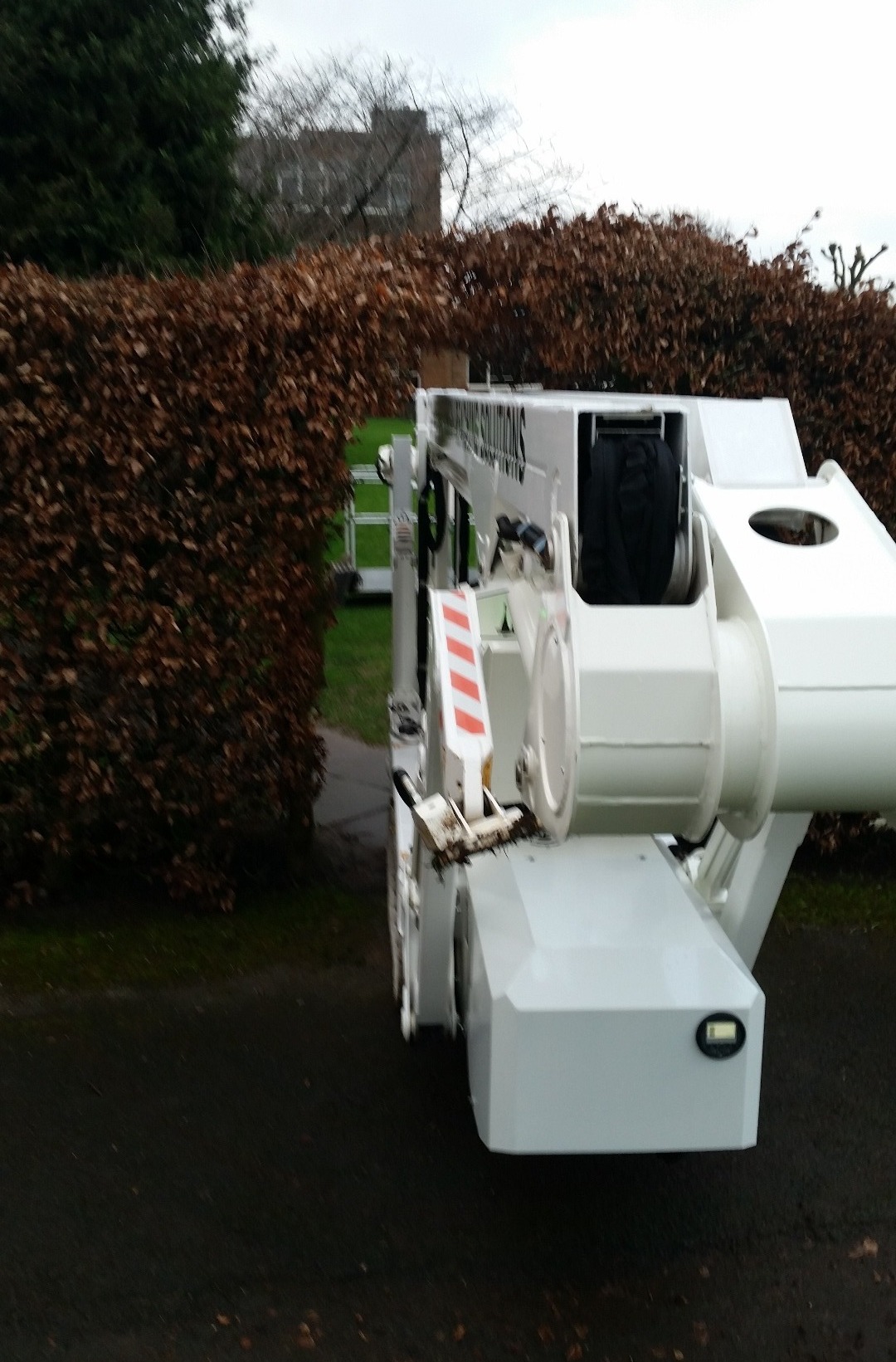 Selina tracked spider cherrypicker going through an archway in a large hedge.