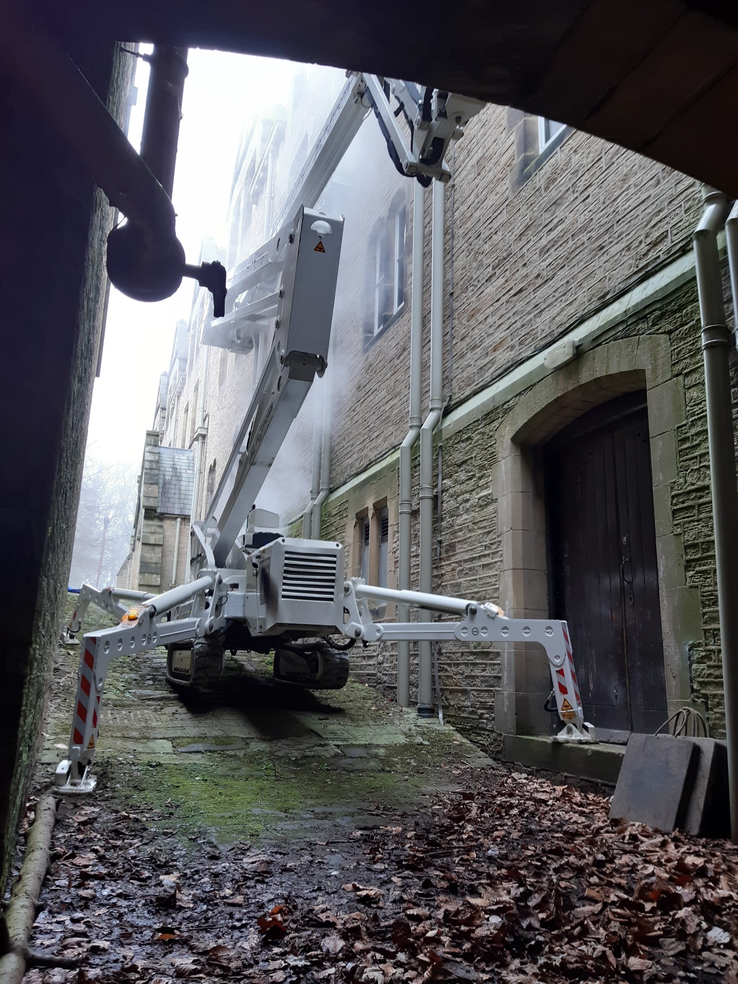 Tracked spider cherry picker in steep sloping stone cobbled alley.